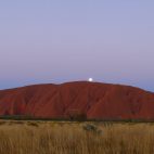 Die Sonne ist gerade untergegangen, als sich der Vollmond über dem Uluru zeigt.